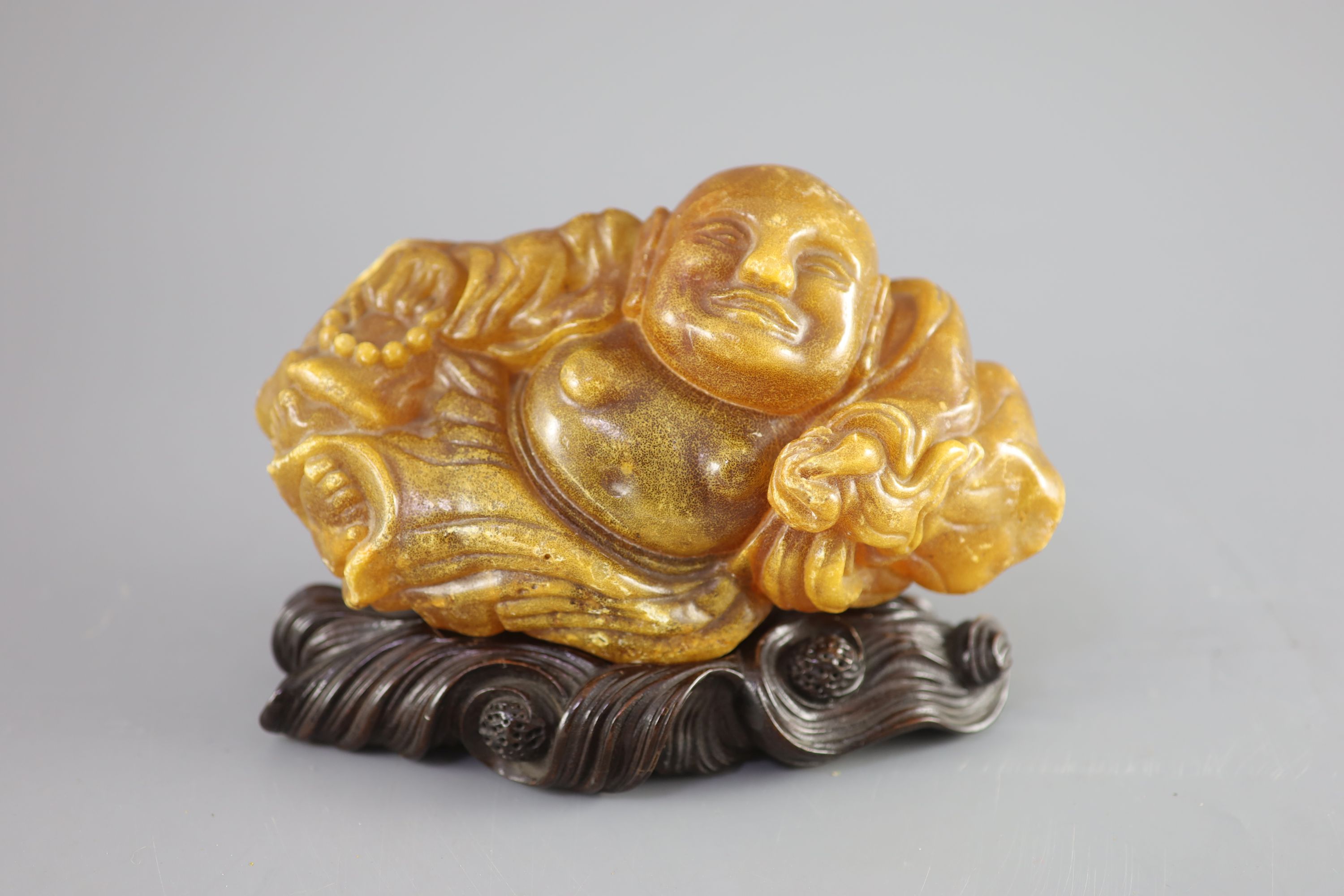 A Chinese amber figure of Buddha, 19th century, width 21.5cm